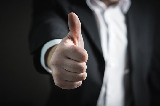 A man in a suit is giving a thumbs up.