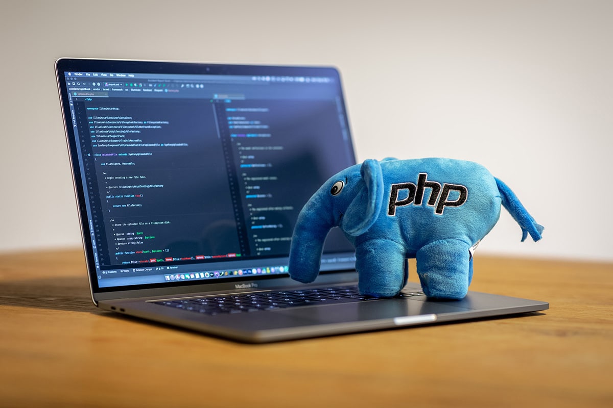 A stuffed elephant with the word PHP on it sits on top of a laptop.