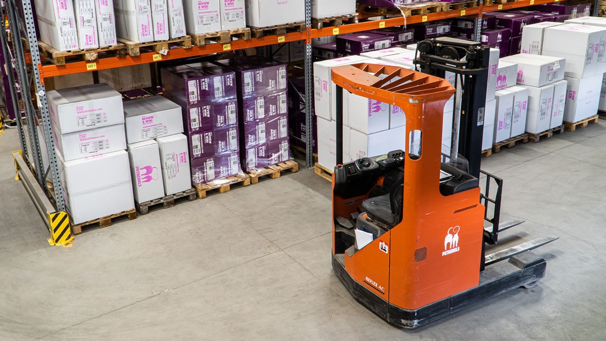 A forklift truck in a warehouse full of boxes.