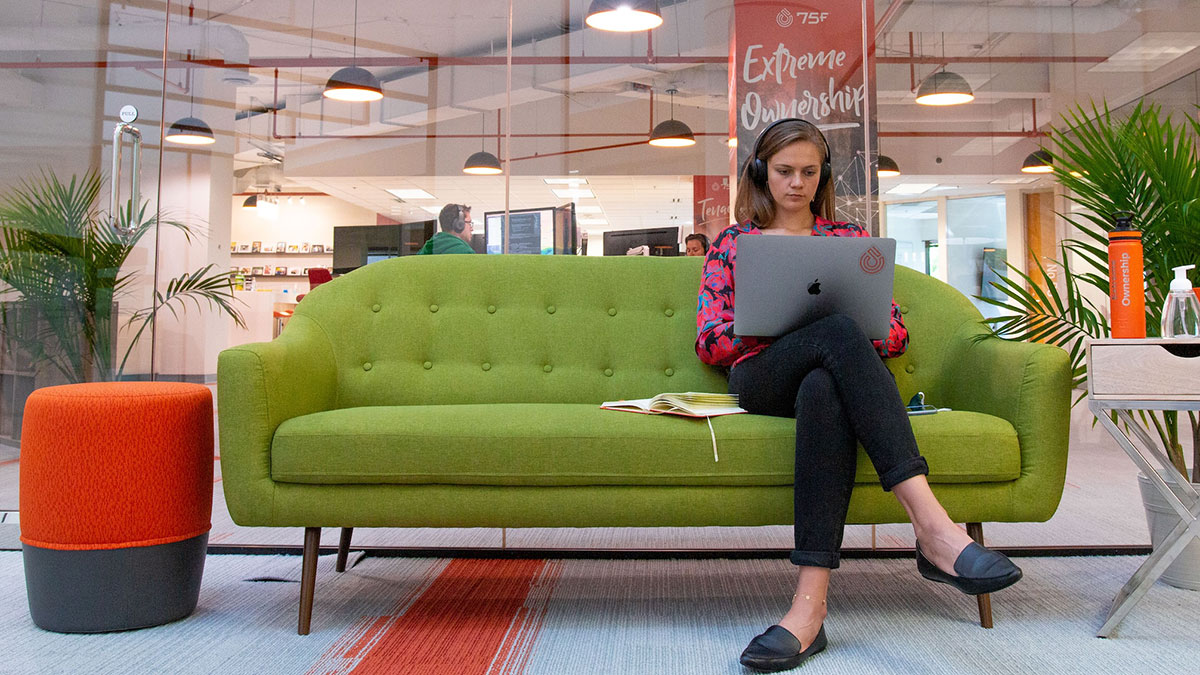 A woman sitting on a green couch planning for the lead generation strategies for her startup.