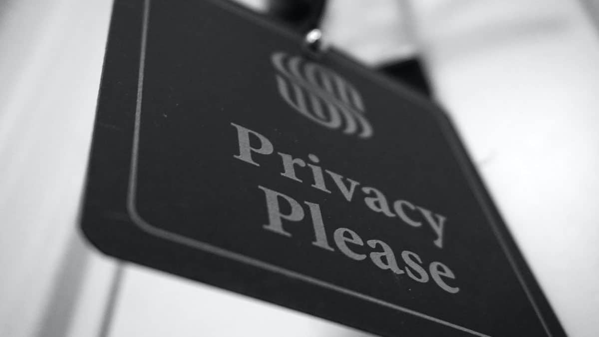 A black and white photo of a privacy sign hanging on a door.