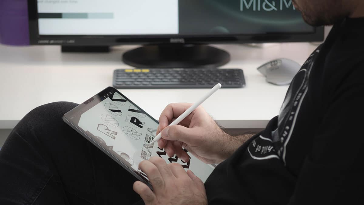 A man is using an apple pencil to draw on an ipad.