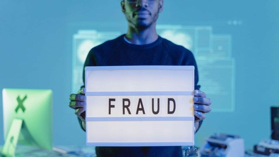 A man holding up a sign that says fraud.