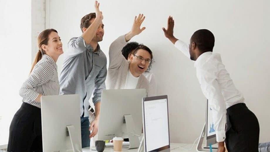 A group of people raising their hands in the air in an office.