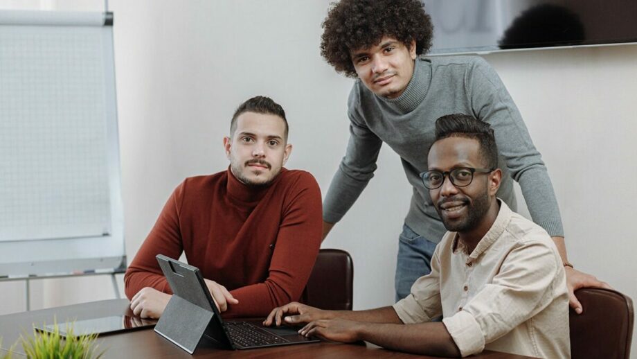 Three men are sitting at a table with a laptop in front of them planning the lead generation strategies for their business startups.