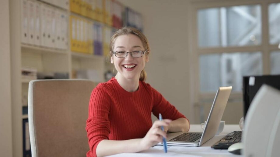 A smiling woman sitting at a desk with a laptop learning content marketing strategy.