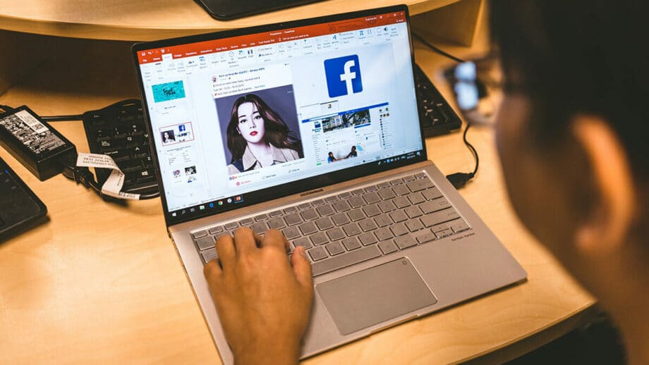 A person using a laptop with facebook on it.