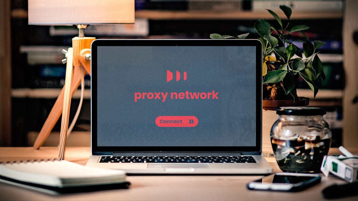A laptop with the word proxy network on it sits on a desk.