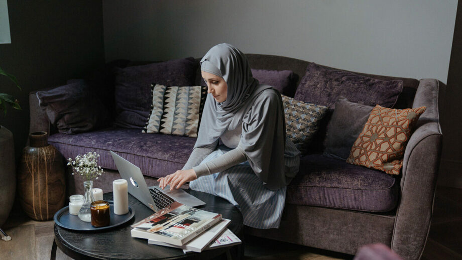 A muslim woman using a laptop in her living room.