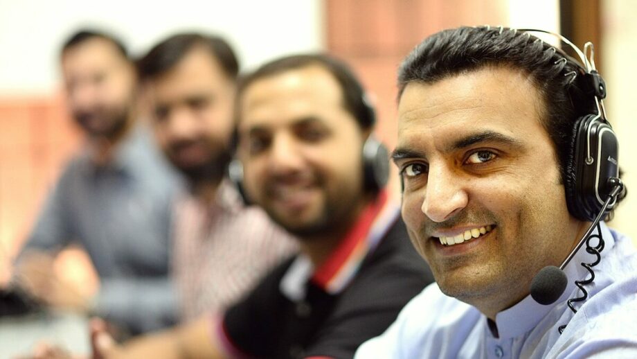 A group of men wearing headsets in a call center.