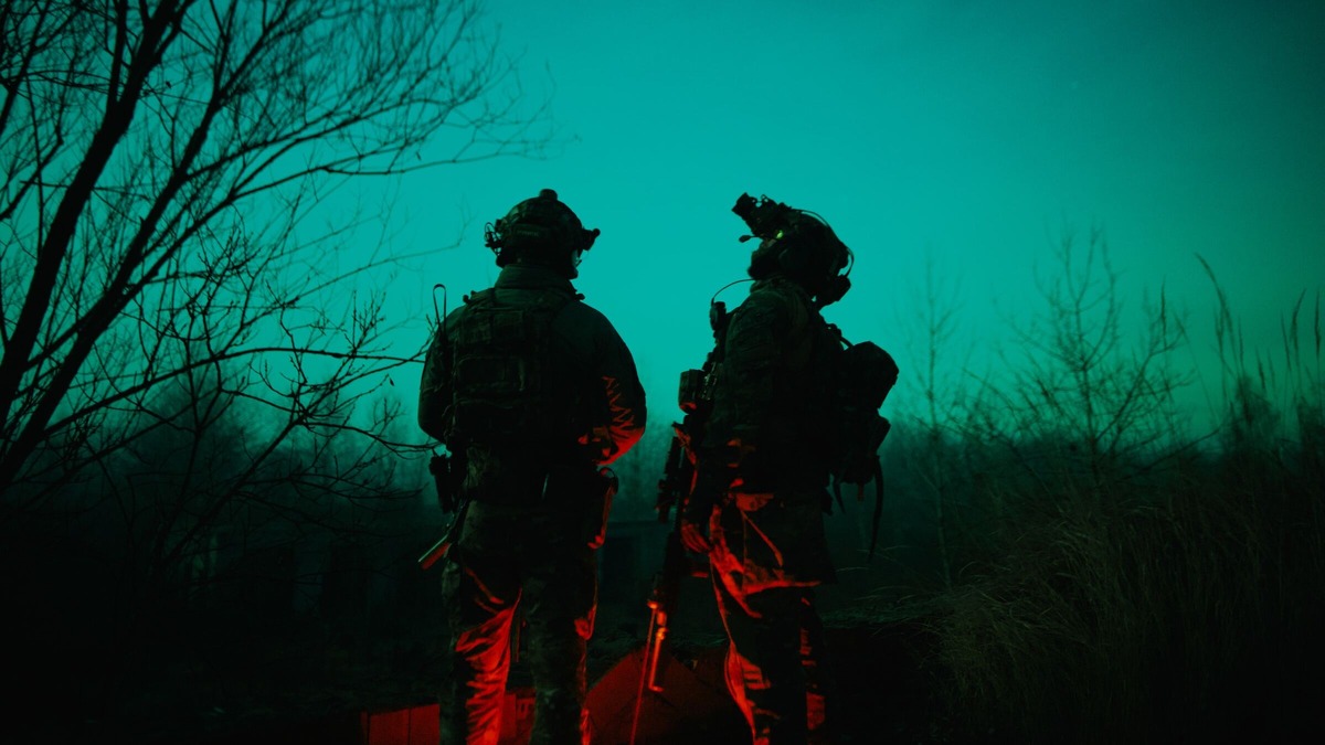Two soldiers standing in the woods at night.