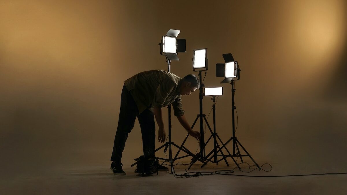 A man setting up lighting equipment in a studio.