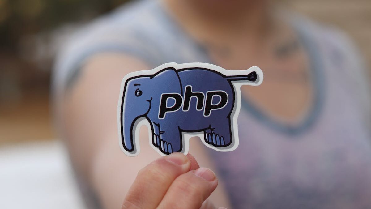 A woman holding up a sticker with the word PHP on it.