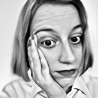A black and white photo of Mika Kankaras, the author of this article, with her hand on her face.