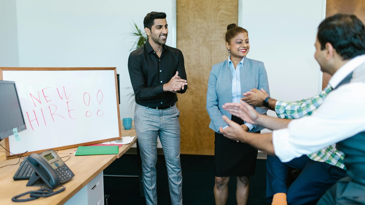 A group of people encouraging an employee in an office in an activity related to positive workplace culture.