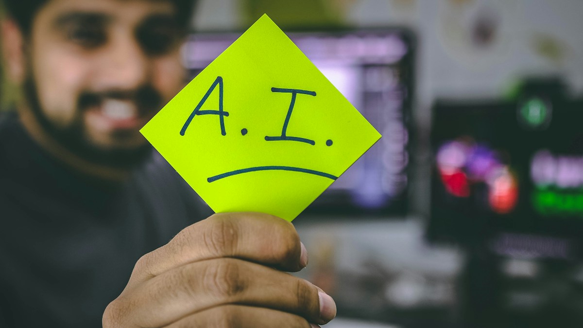 A man holding up a piece of paper with the word ai written on it.