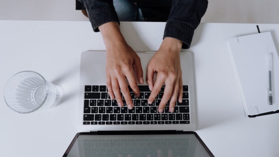 A woman's hands typing on a laptop keyboard.