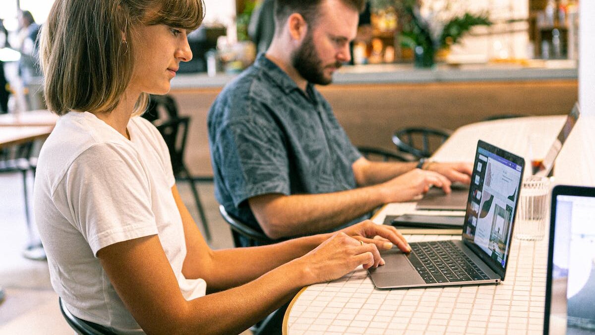 Two people working on laptops in a cafe.